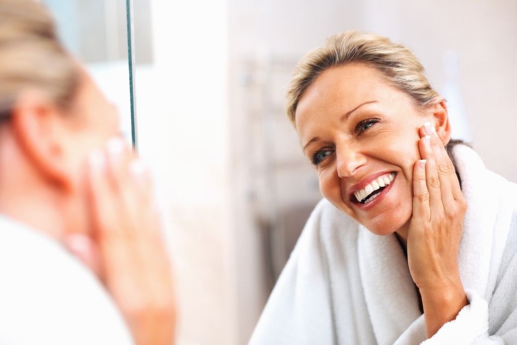 Woman looks into a mirror and smiles
